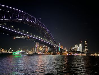 Illuminated bridge over river against sky at night