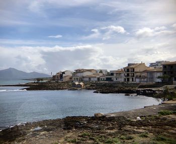 Buildings by sea against sky