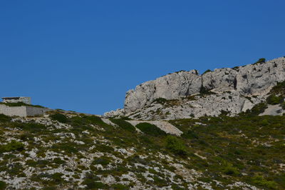 Low angle view of rocks against clear blue sky