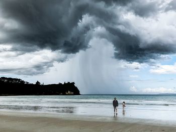 People standing on beach against sky