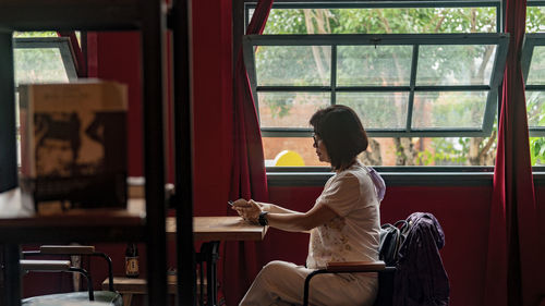 Rear view of woman sitting by window