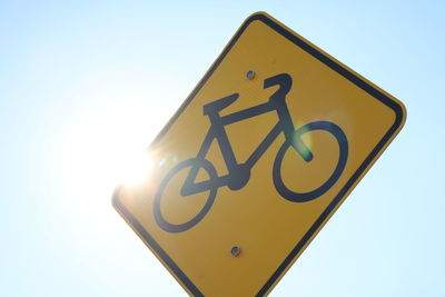 Low angle view of bicycle sign against clear blue sky