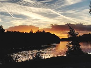 Silhouette trees by lake against sky during sunset