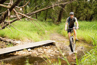 Man riding bicycle on stream in forest