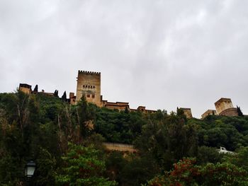 Castle on hill against cloudy sky