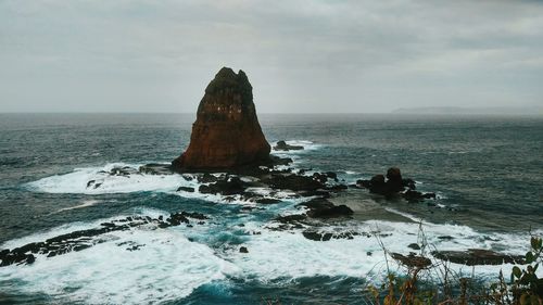 Rock formation in sea against sky