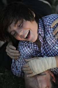 Close-up of cheerful teenager with injured hand falling on father at field
