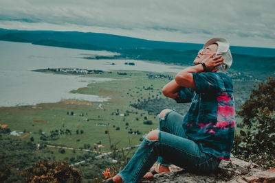 Full length of boy sitting on land against sky