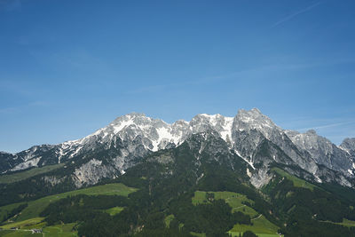 Low angle view of snowcapped mountains against blue sky