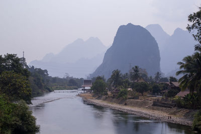 Scenic view of river by mountains against sky