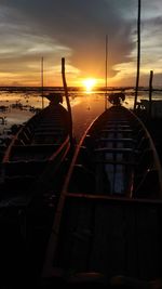 Silhouette boats moored on sea against sky during sunset