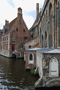 Arch bridge over river by building against sky