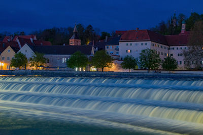 Buildings by swimming pool at night