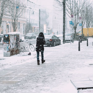 Rear view of man walking on snow covered road