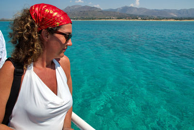 Midsection of woman wearing sunglasses at sea shore