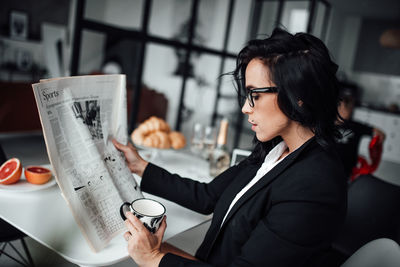 Woman holding drink while sitting at cafe