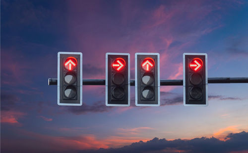 Low angle view of road signal against sky during sunset