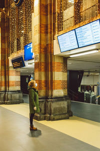 Side view of woman standing by illuminated building