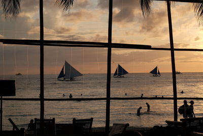 Silhouette people by sea against sky during sunset