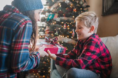 Cheerful woman gift to son at home during christmas 