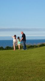 Friends on grassy field against sky