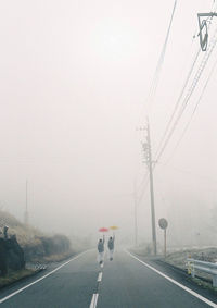 Vehicles on road against sky during foggy weather