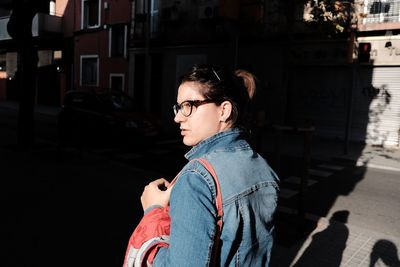 Portrait of young woman standing by street in city