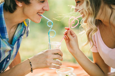 Close-up of smiling couple drinking juice at park