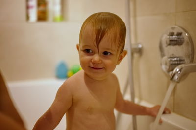 Cute little baby girl having shower in bathtub