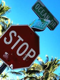 Low angle view of road sign against blue sky