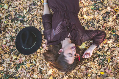 Directly above of smiling woman lying down on land during autumn