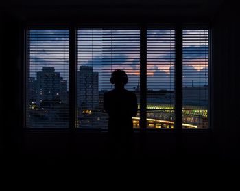 Rear view of silhouette man looking through window