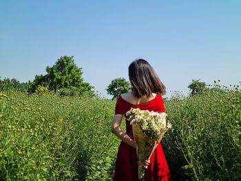 Rear view of woman standing on field against clear sky