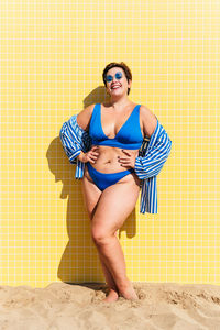 Young woman wearing sunglasses while standing against wall