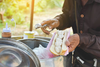 Midsection of vendor holding ice cream sandwich