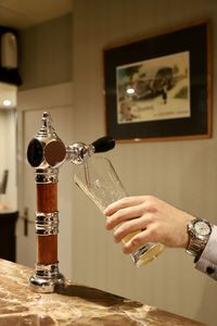Midsection of person pouring drink in glass on table