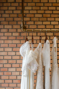 White dresses hanging on coathanger against brick wall