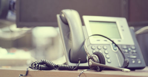 Close-up of telephone and headset on table