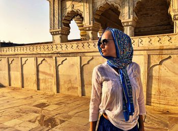 Woman wearing scarf while standing against historic building