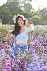 Beautiful young woman standing by flowering plants