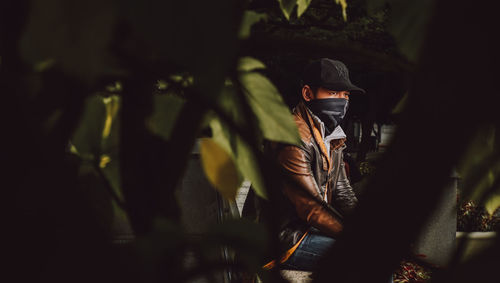 Man wearing mask seen through tree