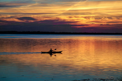 Silhouette of boat in sea during sunset