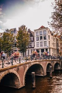 Arch bridge over river in city against sky