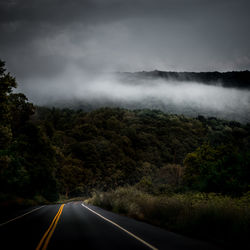 Road by trees against sky