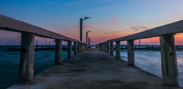 Pier over sea against sky during sunset