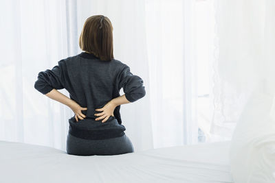 Rear view of woman standing against window