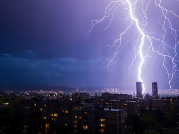 Lightning over illuminated buildings in city at night