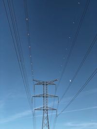 Low angle view of electricity pylon against blue sky