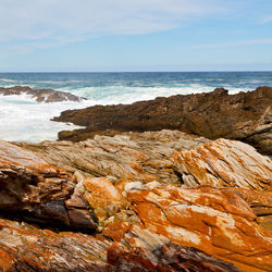 Rock formation on beach against sky