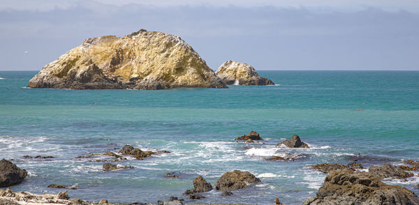Scenic view of rocks in sea against sky